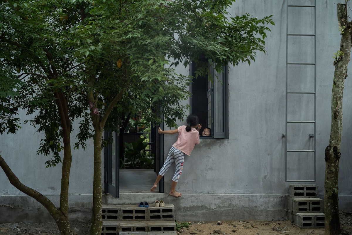 Lối vào chính được bố trí để đảm bảo sự riêng tư, với bức tường khối bê tông chưa hoàn thiện và cửa kính lõm tạo sự tách biệt khỏi đường phố nhưng vẫn duy trì được tầm nhìn từ bên trong.