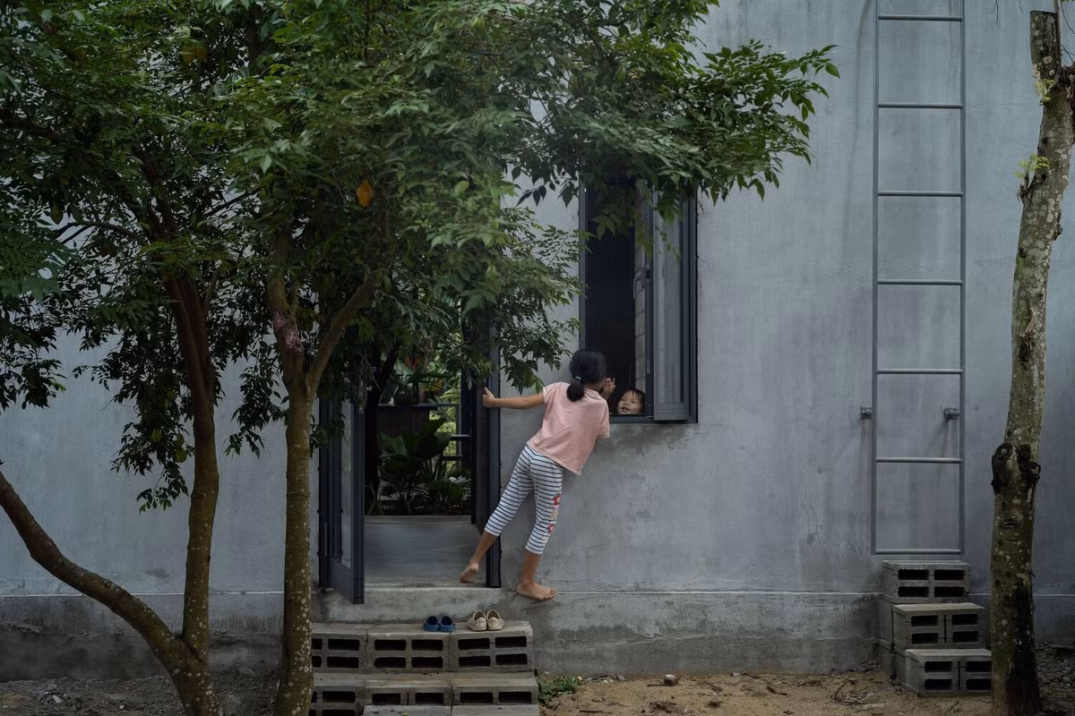 Lối vào chính được bố trí để đảm bảo sự riêng tư, với bức tường khối bê tông chưa hoàn thiện và cửa kính lõm tạo sự tách biệt khỏi đường phố nhưng vẫn duy trì được tầm nhìn từ bên trong.