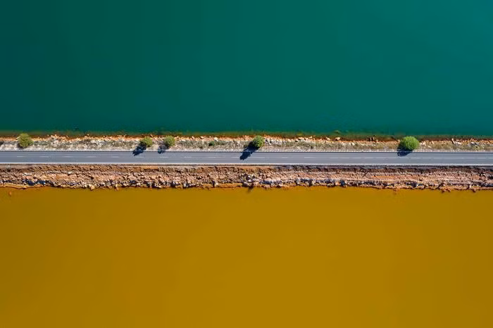 Bức ảnh này có tên "The Life: A narrow strip" chụp tải Huelva, Tây Ban Nha. Trong ảnh là con đường chia đôi hai hồ nước. Một bên là hồ nước sạch màu xanh, bên còn lại là nước ngả màu vàng vì bị ô nhiễm do khu khai thác mỏ của tập đoàn Rio Tinto. Ảnh: Roberto Bueno.