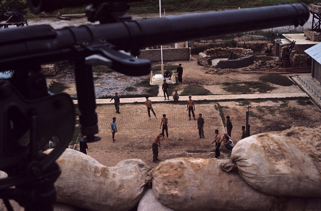 Binh lính chơi bóng chuyền trong sân một doanh trại, nhìn từ ụ súng máy. Ảnh: Jean-Claude Sauer.