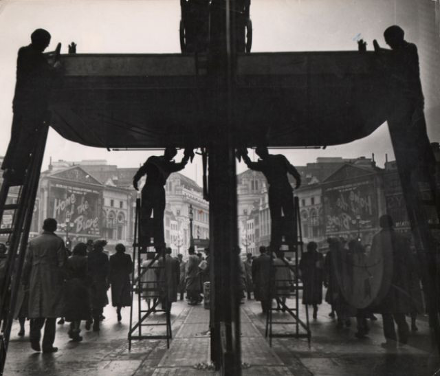 Những người đàn ông đứng trên thang để lau chùi cánh cổng bên ngoài nhà hát Criterion ở khu Piccadilly. Ảnh: Ernst Haas.