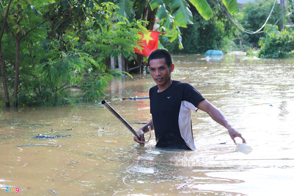 Mưu sinh trong nước lũ dơ bẩn. Để đi được trong lũ, người đàn ông này phải chật vật dò từng mét một.
