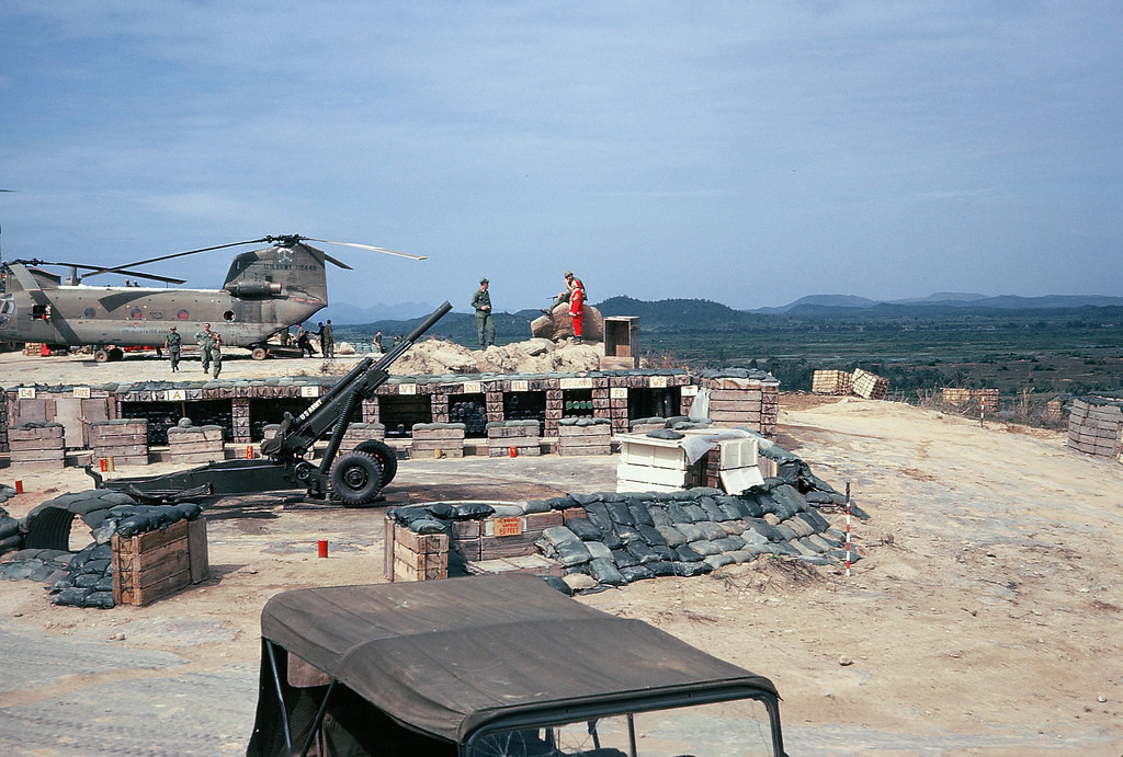 Một góc khu căn cứ với các lô cốt, pháo hạng nặng, trực thăng và xe jeep.