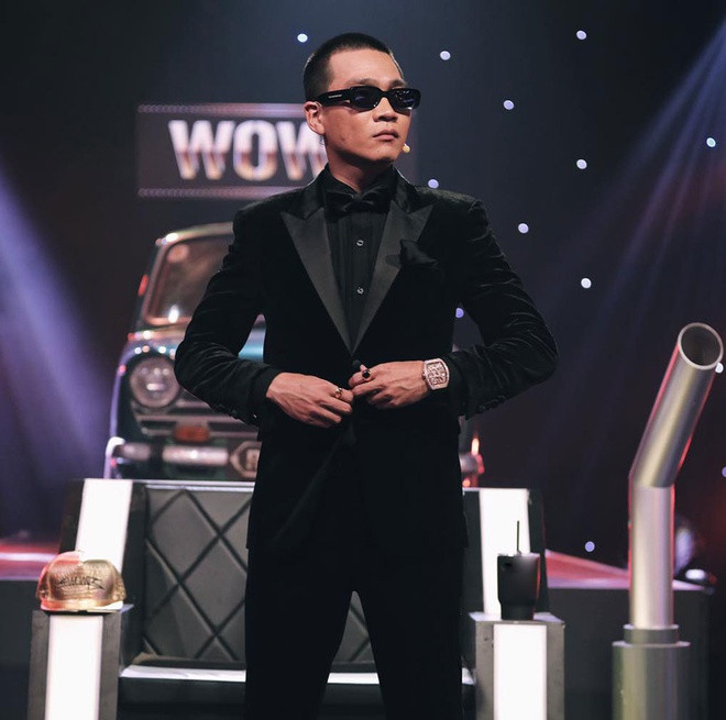 Xuất hiện với vai trò huấn luyện viên trong chương trình Rap Việt, Wowy là cái tên hiện được cộng đồng mạng Việt chú ý. Nam rapper gây ấn tượng trên ghế huấn luyện viên bởi gu ăn mặc đậm chất hip hop những năm 1990. Hình ảnh khiến khán giả nhớ nhất về anh chính là bộ suit đen đeo kính râm và trên tay là đồng hồ đính kim cương lấp lánh của Franck Muller có giá 33.000 USD. Theo chia sẻ của stylist, Wowy muốn mặc trang phục tông đen trong tập chia tay thí sinh. Ảnh: Rap Việt.