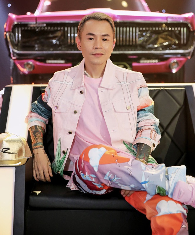 Khác biệt với Suboi, rapper Binz chuộng trang phục có màu sắc sặc sỡ. Anh hướng hình ảnh đến gu ăn mặc đậm chất streetwear cùng gam hồng chủ đạo và họa tiết in theo kiểu tranh vẽ màu nước. Điểm nhấn đến từ cách nam rapper phối sneakers phiên bản giới hạn hợp tác giữa adidas x Raf Simons dòng RS Ozweego. Ảnh: Rap Việt.