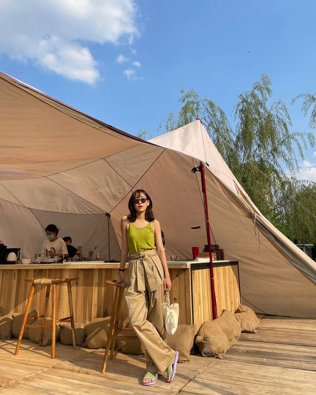 Thời tiết nắng ấm, gái xinh Thái Lan tự tin diện áo ba lỗ màu xanh neon khoe vai thon, bên dưới là quần ống rộng màu nâu nhạt trung tính. Điểm nhấn chính là phần thắt lưng to bản được buộc nhẹ phía trước.