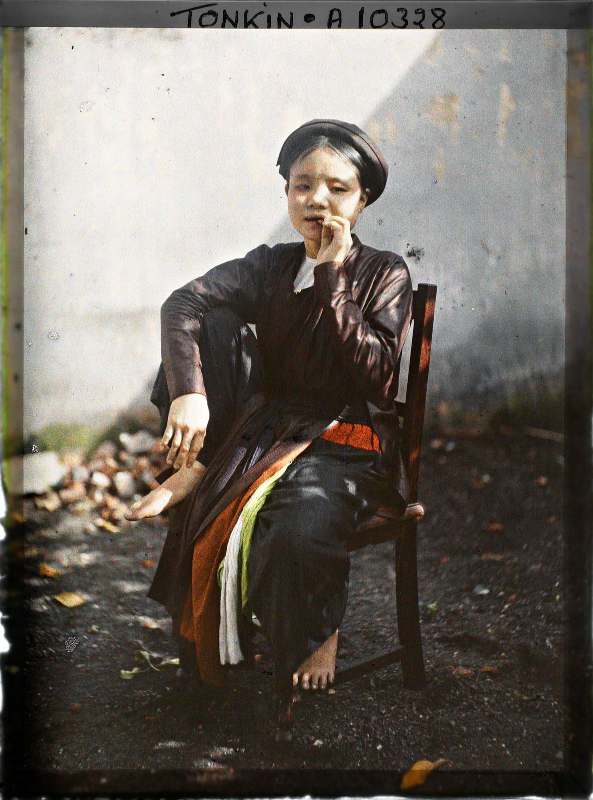 Cô gái ngồi trên ghế gỗ, miệng nhai trầu, 1921.