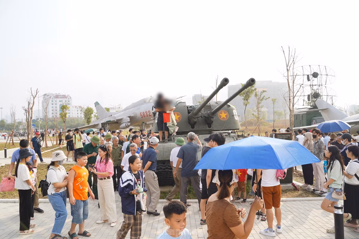 Một phụ huynh bế con leo lên xe tăng đã ngay lập tức bị khách tham quan nhắc nhở.