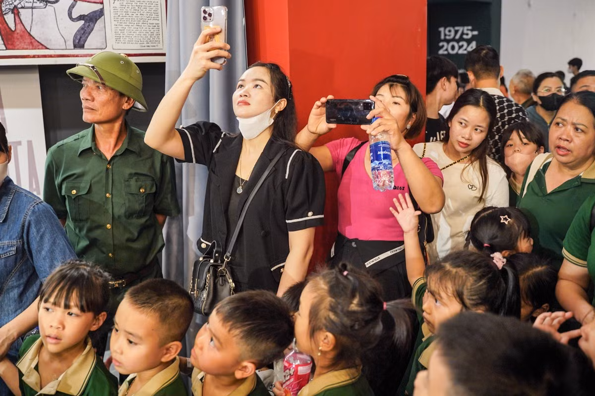 Chị Nguyễn Thị Nguyệt (áo đen, quận Ba Đình) không thể di chuyển đến gần hiện vật nên đã đứng từ xa để chụp ảnh. "Hôm nay khách đông quá, cả tuần đi làm nên cuối tuần tôi mới đến được bảo tàng để tham quan", chị Nguyệt nói.