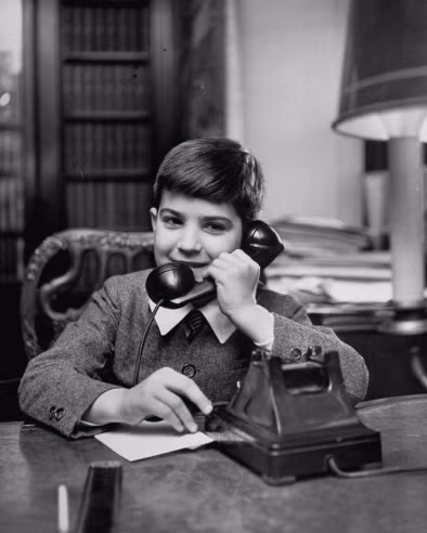 FAO Schwarz là một cửa hàng đồ chơi nổi tiếng tại New York. Để đem lại niềm vui cho những đứa trẻ ngây thơ đang háo hức nhận quà từ ông già Noel, họ đã cài đặt hệ thống điện thoại mà mọi đứa trẻ có thể quay số đó (MU8-2205) và nói chuyện trực tiếp đến “ông già Noel của mình”, với rất nhiều mong muốn được đưa ra từ lũ trẻ: hòa bình thế giới, tình đoàn kết giữa các dân tộc, một bộ xe lửa, một chú thỏ bông... Trong thế giới người lớn, đó những thứ hết sức bình thường, nhưng với lũ trẻ đó lại là niềm vui vô bờ. Ảnh: Cậu bé Christopher Lange, con của một đại biểu Ba Lan tại LHQ, mong muốn một chiếc cặp làm quà Giáng sinh từ ông già Noel.