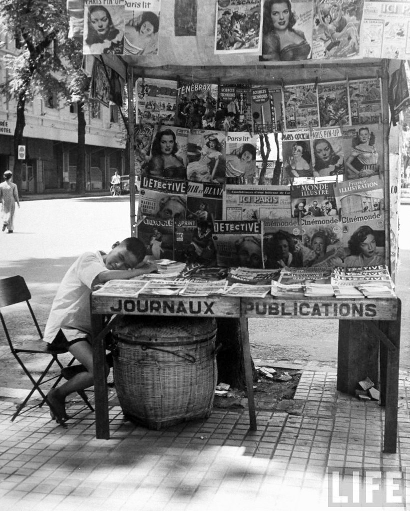Người bán báo ngủ gục trên quầy báo của mình, Sài Gòn năm 1948.