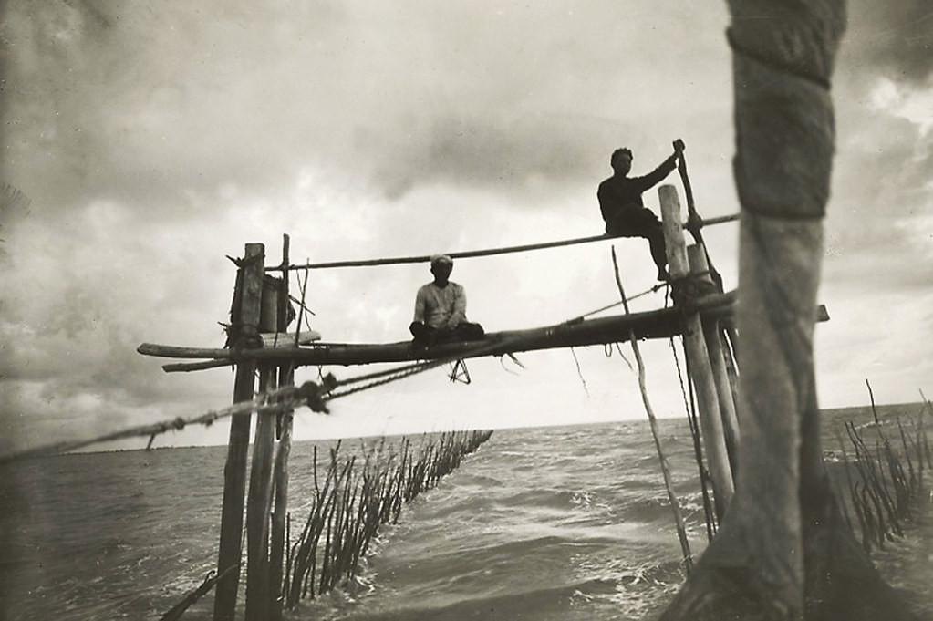 Hai người ngư dân làm việc trên giàn lưới.