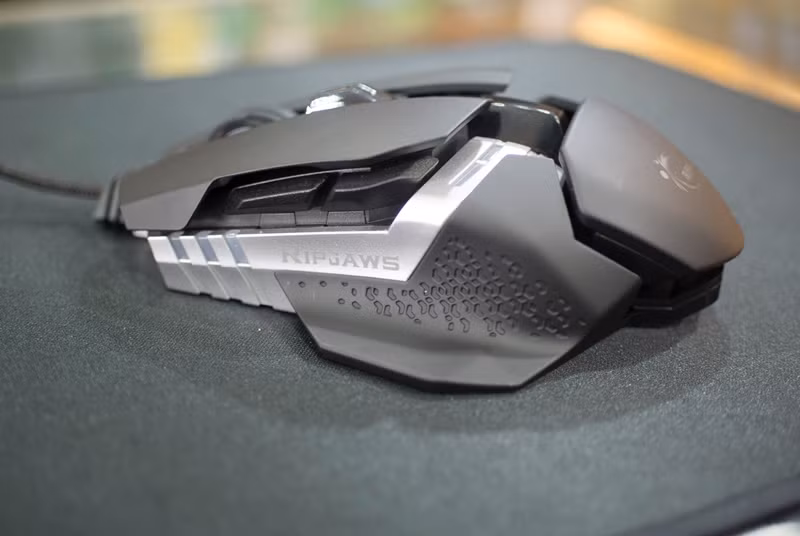 Cạnh trái của chuột với những đường họa tiết cách điệu cùng tông màu xám tạo sự nổi bật và phần cạnh có thể tháo rời để nhét cục tạ đi kèm vào bên trong tạo độ nặng cho chuột. Bên dưới chuột trái sẽ có thêm 2 nút bấm phụ và dễ bấm khi sử dụng.