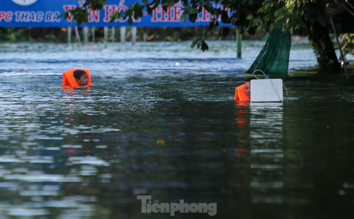 br/> Người dân mặc áo phao, dùng thuyền hoặc di chuyển chậm cạnh khu vực nhà ngập để di dời tài sản.