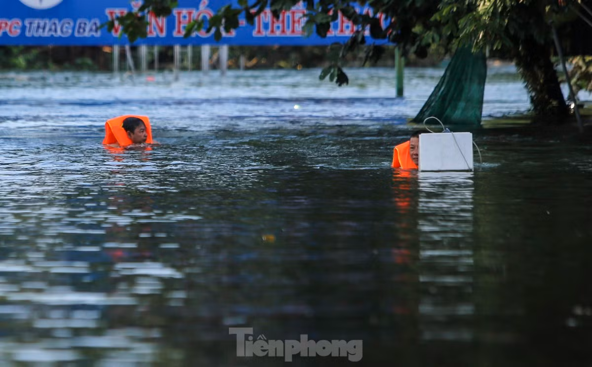 br/> Người dân mặc áo phao, dùng thuyền hoặc di chuyển chậm cạnh khu vực nhà ngập để di dời tài sản.