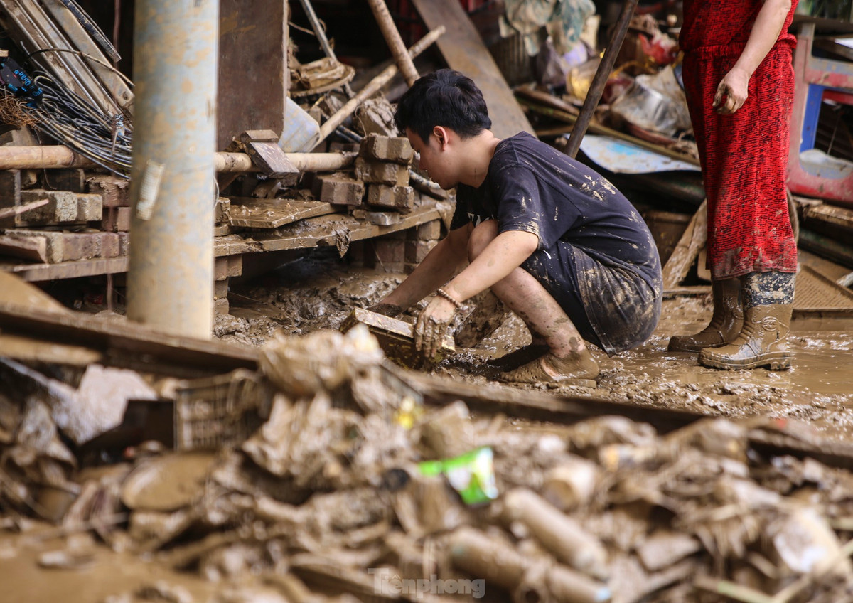 Người dân TP Yên Bái dọn bùn đất sau lũ, tìm kiếm những gì còn dùng được. Đến nay, một số khu vực chưa có điện nên việc gạt bùn gặp khó khăn.
