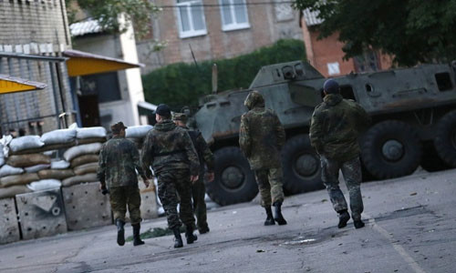 Các dân quân tự vệ đi tới xe quân sự đỗ ở một tòa nhà dân cư.