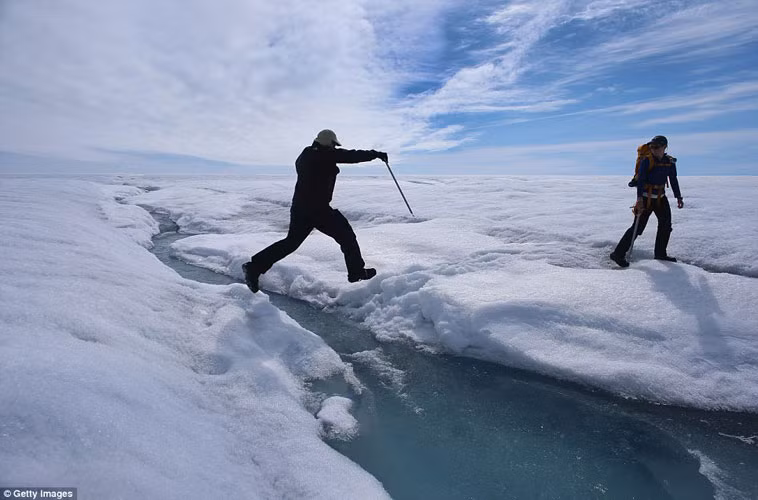 Nhà khoa học Ian Joughin của Đh Washington nhảy qua một dòng suối nhỏ đang chảy trên sông băng.