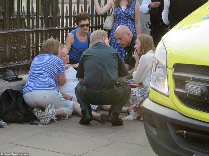 Một phụ nữ hòa trong dòng người đứng đợi tin vui trước cung điện Buckingham có biểu hiện bị choáng.