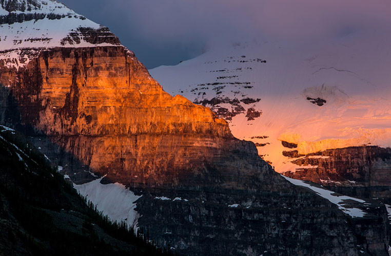 Vẻ đẹp ngoạn mục của ngọn núi đá phủ tuyết trắng ánh đỏ trong nắng ở công viên Banff.
