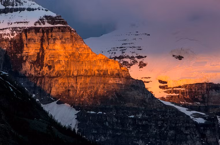 Vẻ đẹp ngoạn mục của ngọn núi đá phủ tuyết trắng ánh đỏ trong nắng ở công viên Banff.