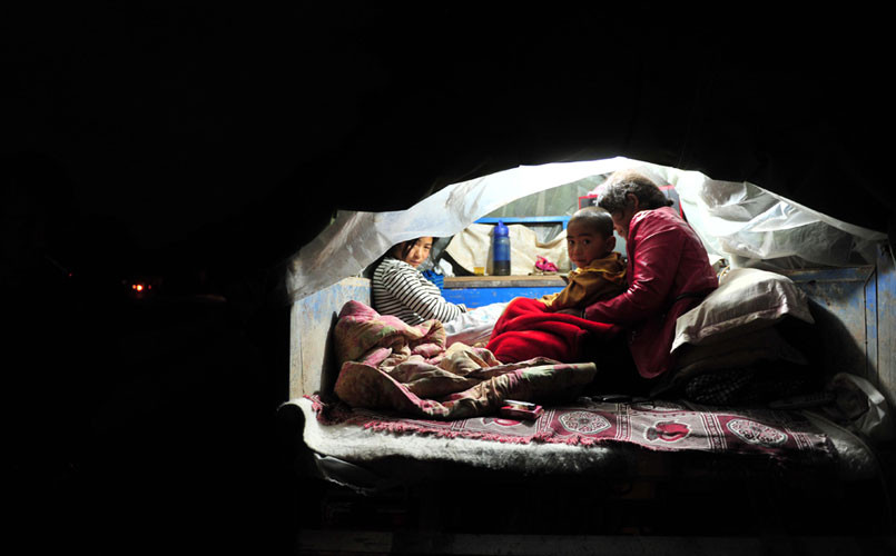 Một gia đình ở Minxian, Trung Quốc ngồi trên chiếc xe 3 bánh sau khi trận động đất mạnh 6,6 độ richter làm rung chuyển huyện Minxian và Zhangxian, tỉnh Cam Túc ngày 23/7 giật sập ngôi nhà của họ, làm ít nhất 95 người thiệt mạng và hơn 1.000 người bị thương.