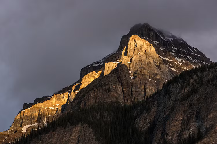 Nắng nhuộn vàng một phần dãy núi đá sừng sững.