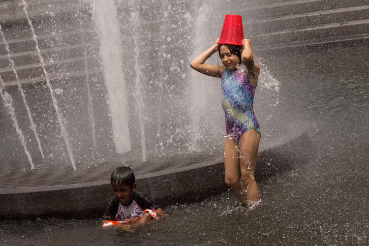 Bé Mary, 8 tuổi(phải) và em trai Micah, 6 tuổi, chơi đùa trong đài phun nước ở quãng trường Washington, New York ngày 15/7 khi miền Đông Mỹ đang trong đợt nắng nóng gay gắt.