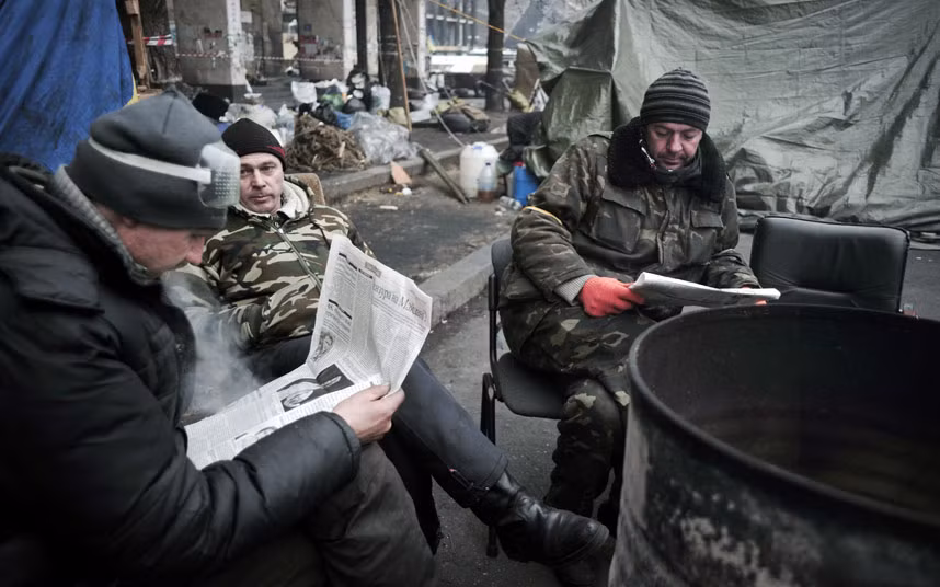 Người biểu tình Ukraine ngồi đọc báo tại một khu vực họ chiếm đóng trong suốt phong trào biểu tình chống chính phủ ba tháng qua.