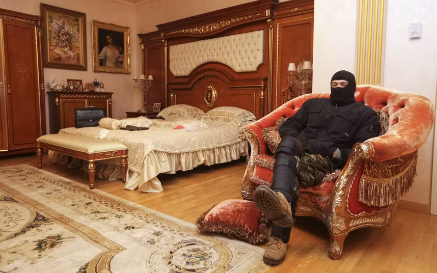 Một người biểu tình ngồi trên chiếc ghế sang trọng trong phòng ngủ của tòa biệt thự thuộc sở hữu của cựu Trưởng Công tố viên Ukraine, Viktor Pshonka ở ngoại ô Kiev. Cựu Trưởng Công tố viên Ukraine Viktor Pshonka - người đang bị truy nã - đang chạy trốn và không rõ tung tích.