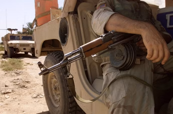Một lính Mỹ đang cầm khẩu AK với hộp tiếp đạn tròn, Baqouba, Iraq năm 2003.