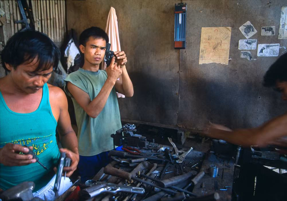 Bên trong một xưởng sản xuất súng ở thành phố Danao, 1995. Đây là thành phố nổi tiếng với ngành công nghiệp súng ống có lịch sử từ đầu thế kỷ 20. Chính quyền Philippines thập niên 1990 đã hợp thức hóa ngành này bằng việc thành lập hai nghiệp đoàn quy tụ các cơ sở sản xuất nhỏ lẻ trước đây. Ảnh: Hiroji Kubota/ Magnum Photos.