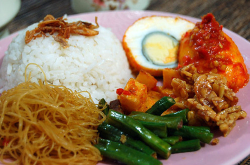 Nasi Uduk hay còn gọi là cơm nước cốt dừa, tên gọi này xuất phát từ cách chế biến của món ăn. Ngoài hương thơm dậy của chén cơm nấu cùng nước cốt dừa, Nasi Uduk còn mời gọi du khách với hàng loạt món phụ khác như thịt tẩm gia vị, cá, thịt gà, trứng luộc, xốt ớt và bánh quy giòn.