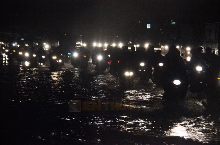 Trời trời mưa như trút nước, người dân vượt lũ và bóng đêm về nhà.