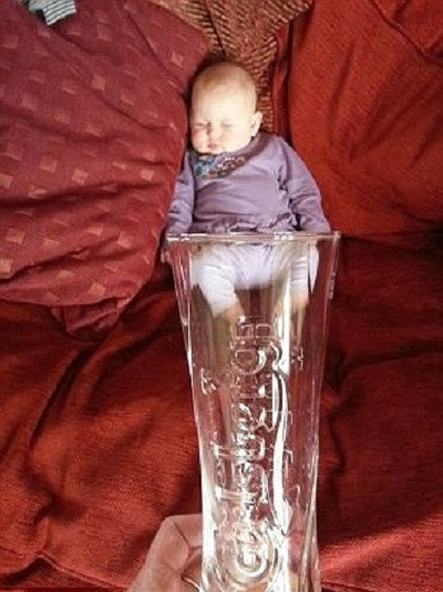 Em bé oằn nửa mình trong chiếc cốc thủy tinh trong suốt.