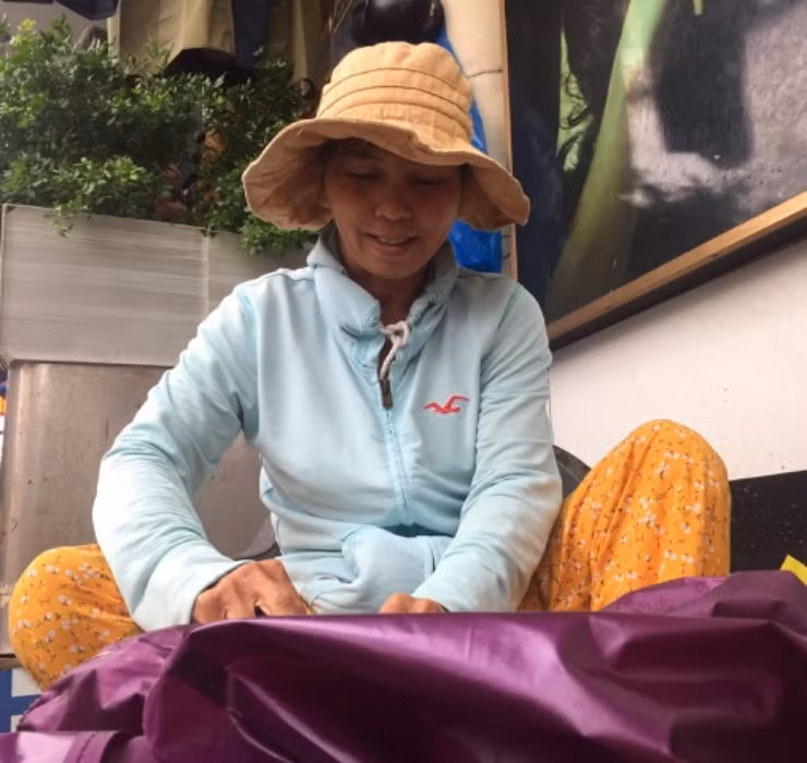 Cô Lê Thị Xuân Lành - một thợ sửa áo mưa với hơn 20 năm kinh nghiệm chia sẻ, mỗi lần muốn vá áo, trước tiên cần kiểm tra độ rộng chỗ rách để có thể cắt được mảnh ghép phù hợp.