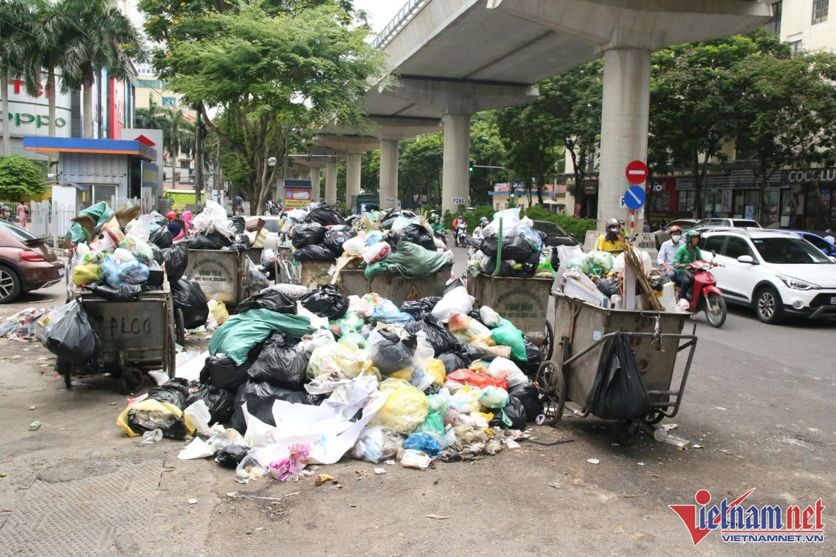 Trên tuyến đường Xuân Thuỷ, rác thải ùn ứ đã nhiều ngày nay. Vào chiều 17/6, công nhân môi trường thu gọn những chiếc xe gom, chờ xe tải xử lý rác thải đến
