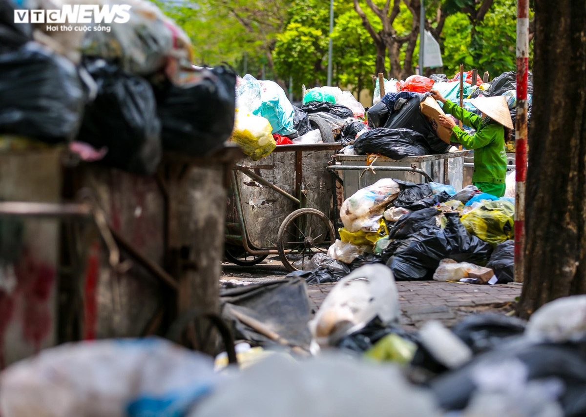Công nhân trên tuyến đường Duy Tân (Hà Nội) đang hoạt động thu gom rác, sau khi thu gom xong, các công nhân sẽ phủ bạt chờ xe đến.