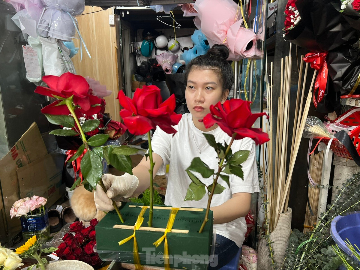 Nhân viên tiệm hoa cắm hoa theo yêu cầu của khách.