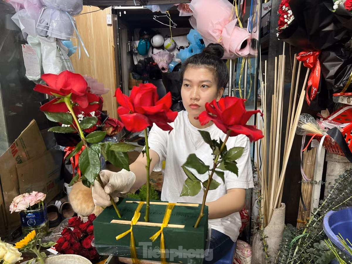 Nhân viên tiệm hoa cắm hoa theo yêu cầu của khách.
