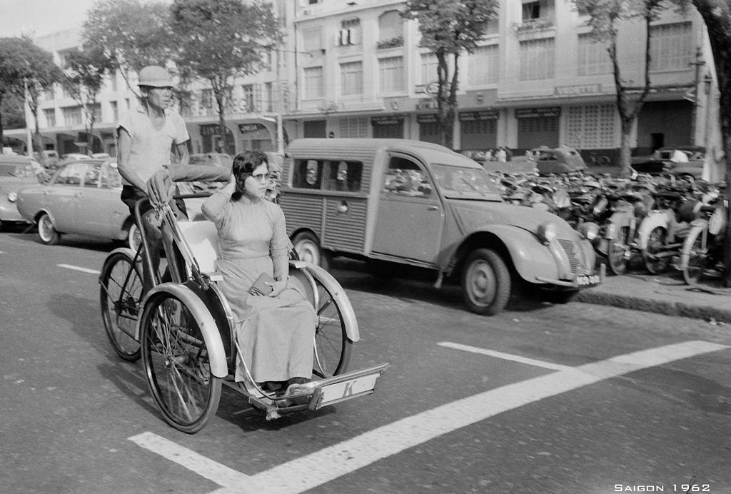 Người phụ nữ áo dài đi xích lô trên đại lộ Lê Lợi.