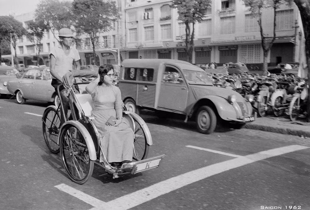 Người phụ nữ áo dài đi xích lô trên đại lộ Lê Lợi.