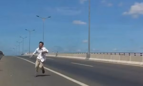 Khuôn mặt tươi cười của người đàn ông lao vào gầm xe tải, khi xe đã chạy qua.