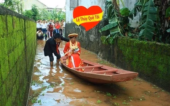 Cộng đồng mạng xã hội đang "sốt xình xịch" với bức ảnh chụp lại cảnh chú rể xắn quần, đẩy cô dâu ngồi trên thuyền nhỏ đi qua đoạn đường đang bị ngập vì mưa lũ (do ảnh hưởng của bão Nari vừa qua) về dinh, còn đứng phía ngoài là bạn bè, người thân của đôi bạn trẻ. Cho dù đám cưới đúng mùa mưa lũ, khó khăn, nhưng đôi bạn trẻ vẫn nở nụ cười hạnh phúc. (Ảnh: FB Lệ Thủy Quê Tôi).