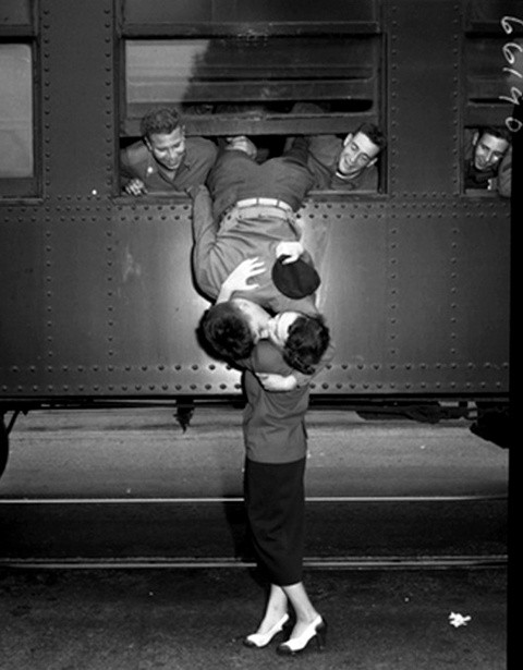 Hình ảnh người lính nhờ sự trợ giúp của đồng đội trèo ra ngoài cửa sổ tàu hỏa để hôn tạm biệt vợ vào năm 1950. Ảnh chụp tại California, Mỹ