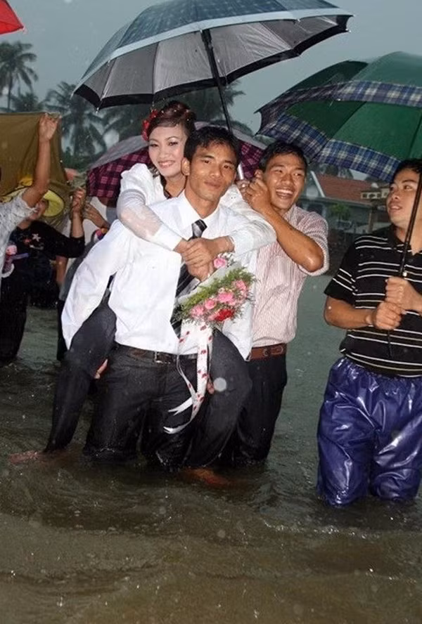 Chú rể đội ô cõng cô dâu vượt qua cánh đồng mênh mông nước lũ. (Đám cưới tại Hương Sơn, Hà Tĩnh).