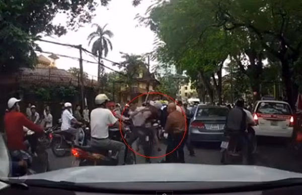 Người đàn ông trung tuổi, mặc áo da cam, đầu cạo trọc can ngăn nam thanh niên hùng hổ. (Ảnh cắt từ clip).