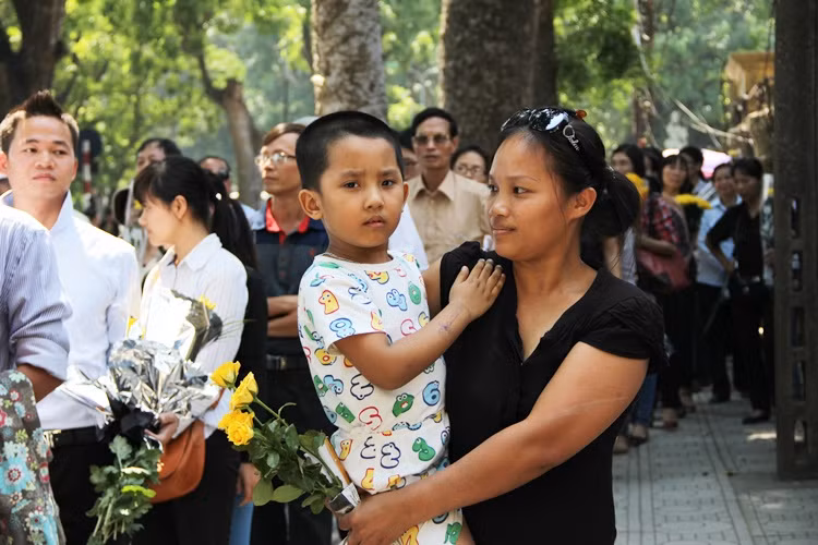 Cậu bé được người mẹ bế xếp hàng cùng mọi người, đợi vào thắp nén tâm hương cho Đại tướng.