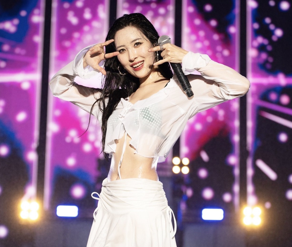 Sunmi mặc áo sơ mi dài tay dáng croptop cùng chân váy trắng, bên trong là nội y màu xanh trông cá tính và gợi cảm.