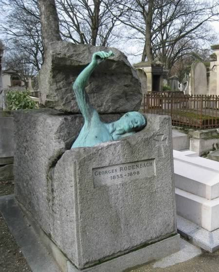 7. Tư thế ám ảnh của người chết: Pere Lachaise ở Paris là nghĩa trang có nhiều người đến thăm nhất thế giới và nó nổi tiếng không chỉ bởi vẻ đẹp của các bức tượng, mà còn bởi những người danh tiếng đã được mai táng tại đây. Một trong số những ngôi mộ ám ảnh nhất thuộc về một văn sỹ mà nhiều người chưa được nghe tên. Georges Rodenbach là một nhà văn người Bỉ sống ở thế kỷ 19 có tiếng về viết phần lớn sách văn học nghiêm túc dành cho sinh viên. Cuốn “Bruges la Morte” là một tiểu thuyết mang tính biểu tượng được xuất bản vào năm 1892 nói về một người đàn ông rất đau buồn bởi người vợ đã quá cố của mình. Hình ảnh Rodenbach ở tư thế đang đứng dậy từ ngôi mộ của chính mình trên tay cầm một bông hồng khiến người ta xúc động.